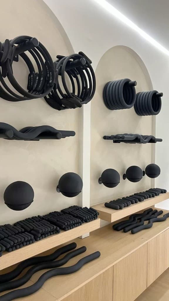 Reset Pilates studio, equipment wall with arches, timber shelving and matte black props